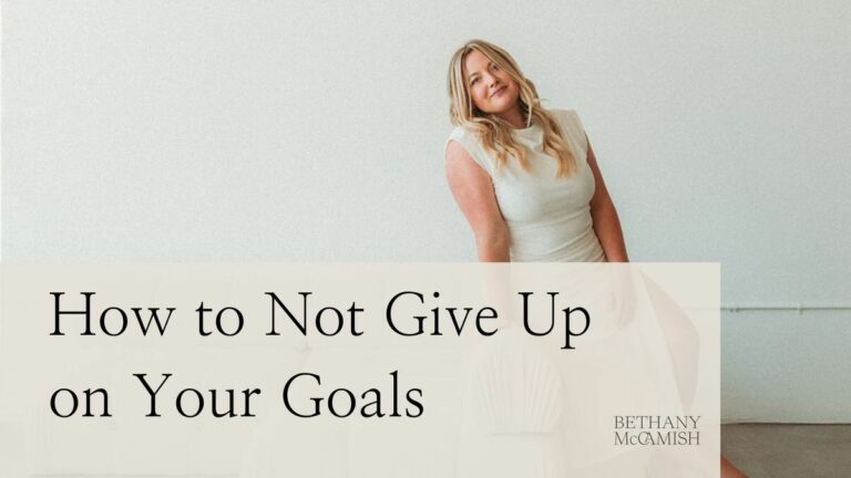 A motivational blog post header featuring a smiling woman leaning against a white wall with text overlay 'How to Not Give Up on Your Goals' by Bethany Mcamish